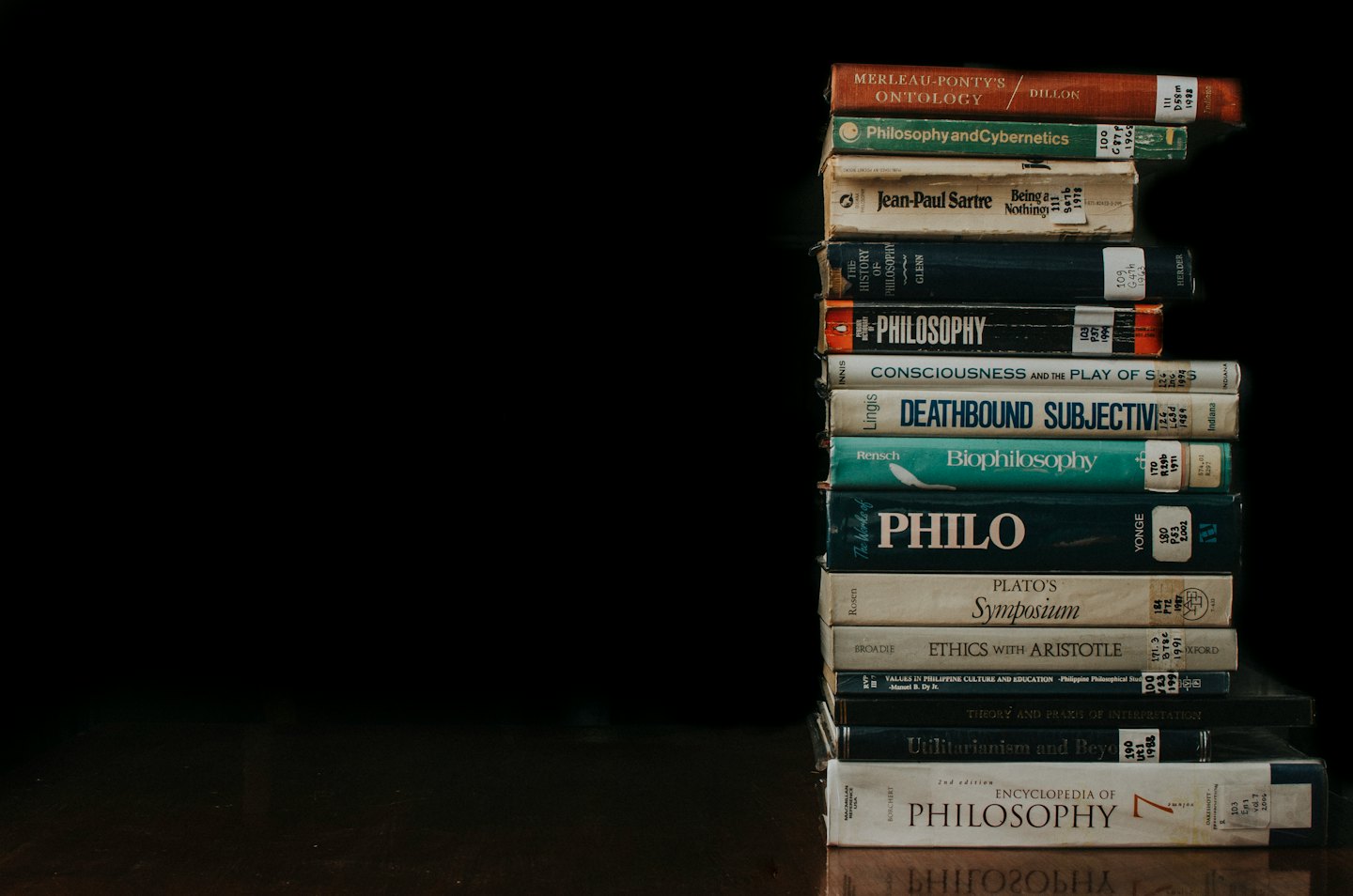 Pila di libri di filosofia diversi su una superficie scura.