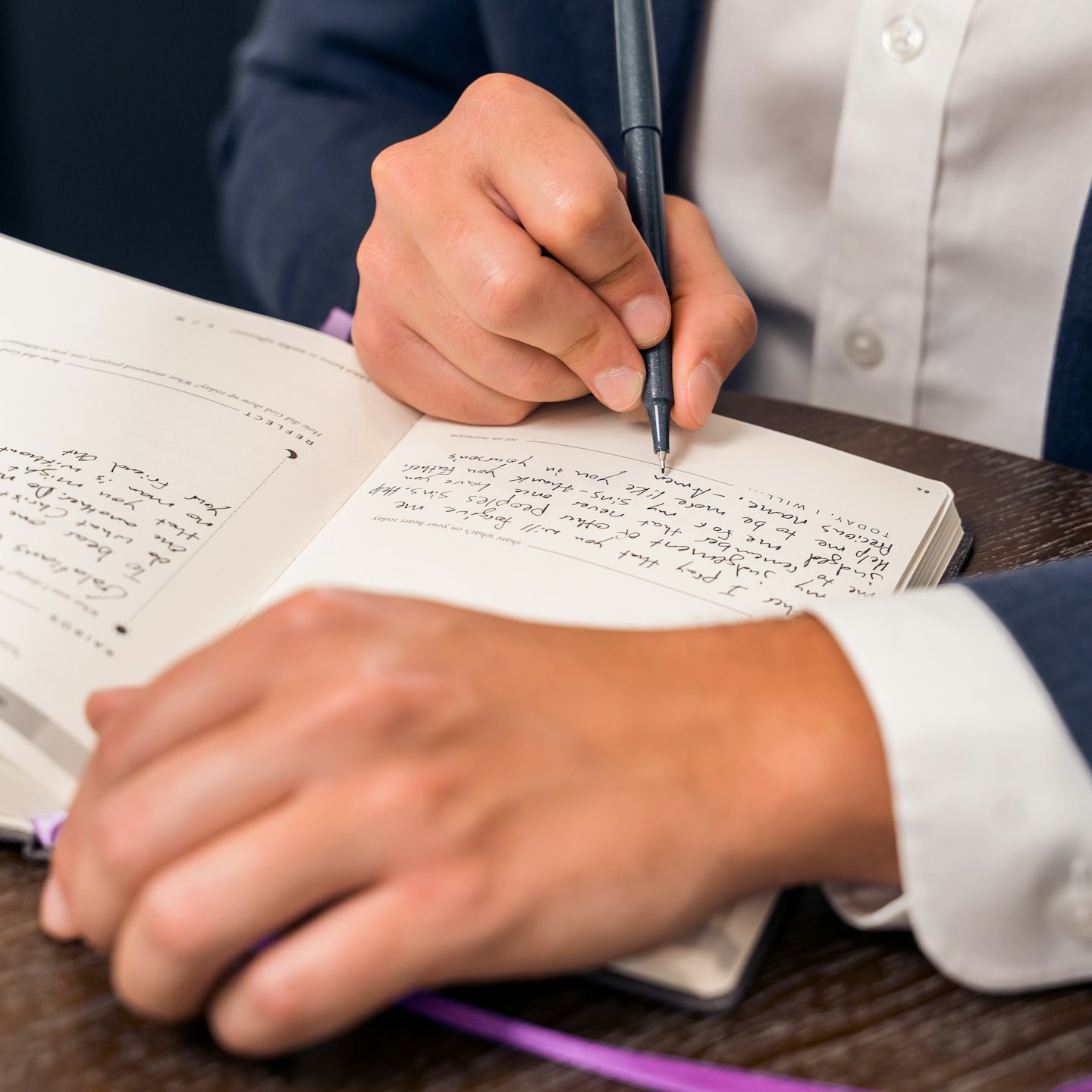 Persona che scrive su un diario con una penna.